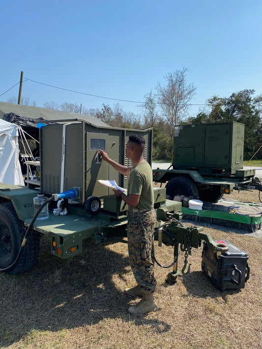 U.S. military serviceman inspecting RussKap mobile Atmospheric Water Generation (AWG) unit.